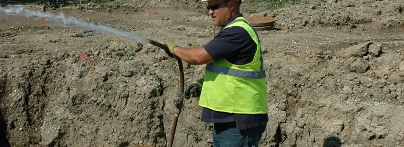 A man in yellow vest holding a shovel.